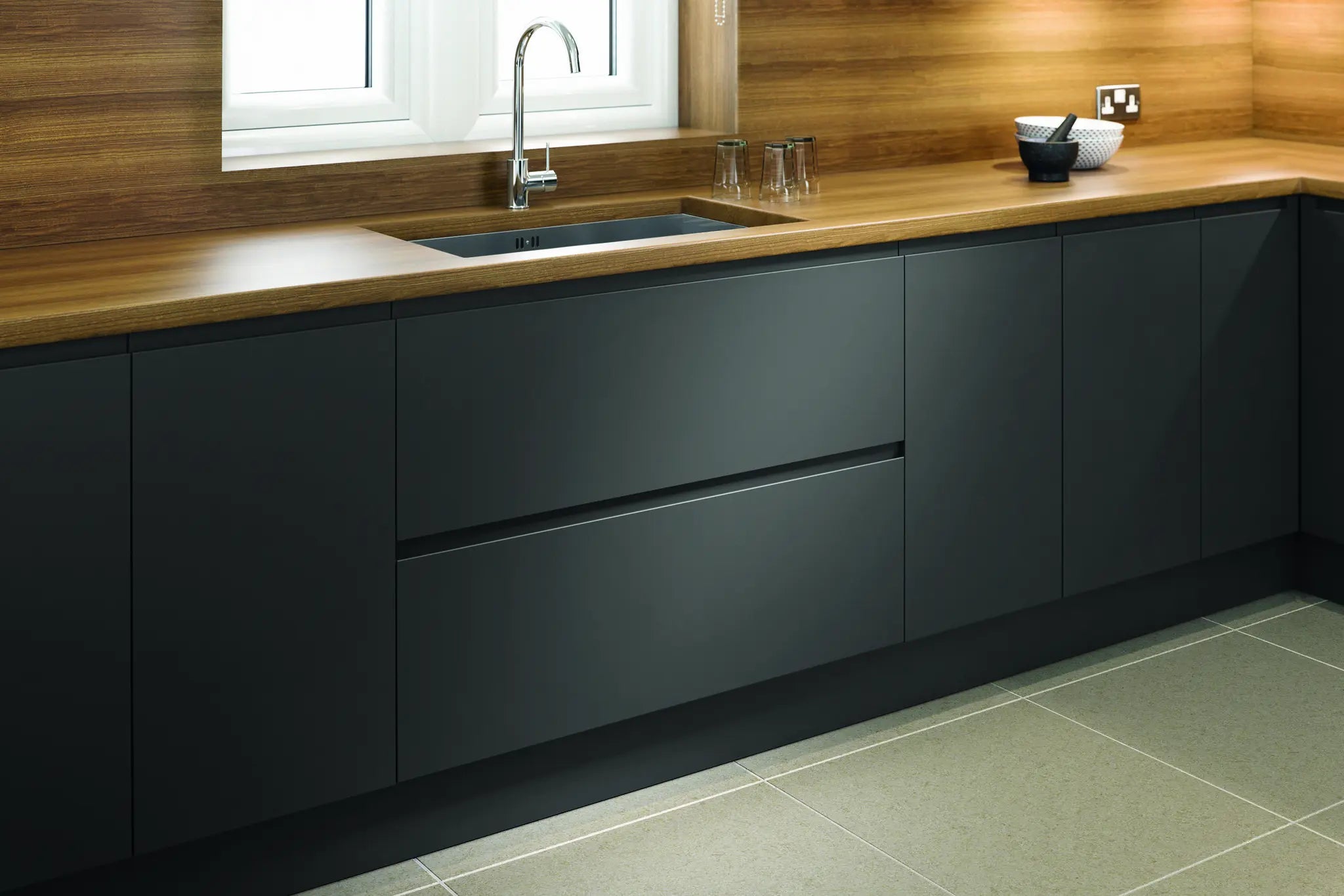 Modern Lucente kitchen with dark grey cabinets, wooden countertop, and tiled floor.