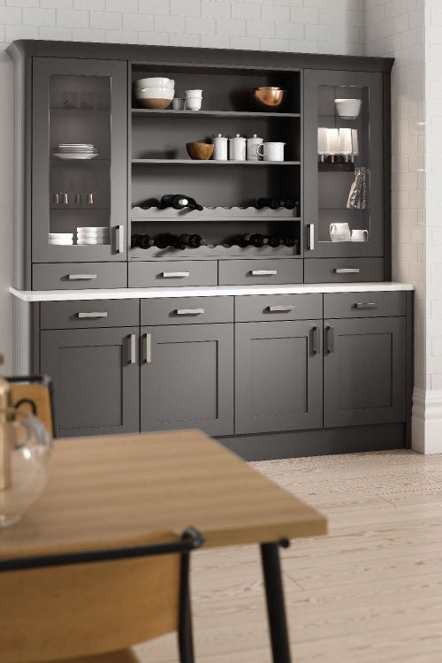Grey kitchen cabinet with shelves and drawers in a room with wooden floor and white walls.