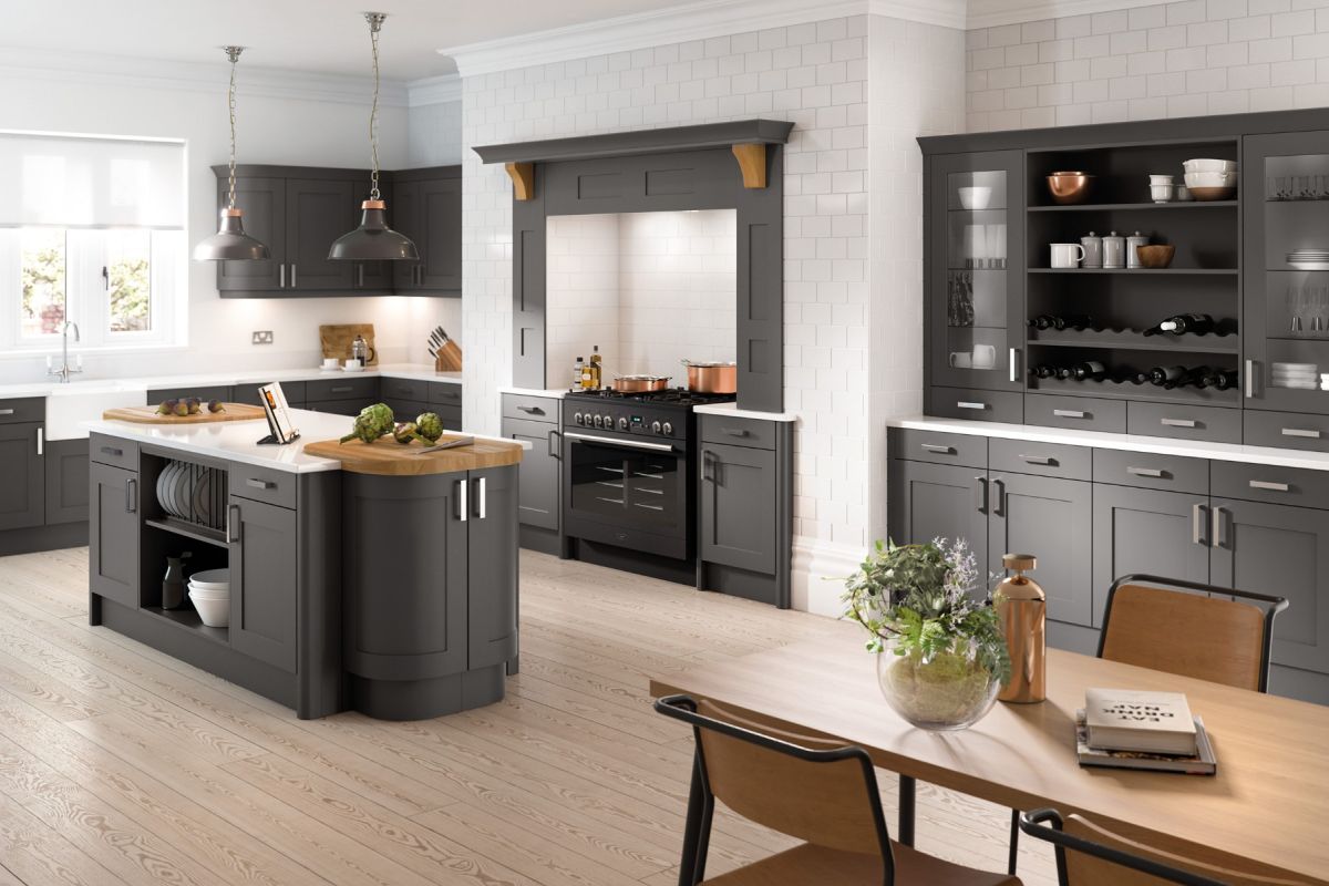 Modern kitchen with dark grey island and cabinets, wooden dining table, and white walls.