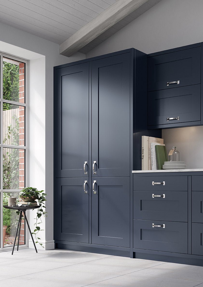 Indigo Oxford Larder with silver handles in a room with a window and plant.