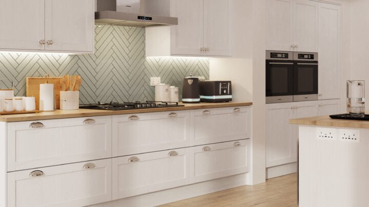 Modern kitchen with light grey cabinets, wooden countertops, and stainless steel appliances.