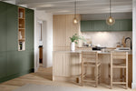 Modern kitchen with green cabinets, wooden island, and bar stools.