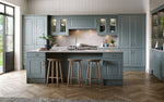 Modern kitchen with grey cabinets, wooden floor, and bar stools.