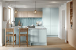 Modern blue and oak kitchen with light blue tiles, wooden chairs, and pendant lights.