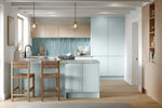 Modern Bella Knebworth blue and oak kitchen with light blue tiles, wooden chairs, and pendant lights.