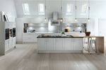 Modern kitchen with light grey cabinets, wooden island, and skylights.