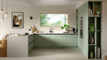 Modern kitchen with green cabinets, white countertops, and a window view.