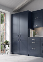 Indigo Oxford Larder with silver handles in a room with a window and plant.