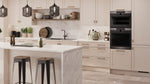 Supermatt Cashmere Waterford kitchen with white marble island, black appliances, and wooden stools.