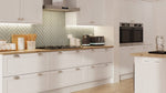 Modern kitchen with light grey cabinets, wooden countertops, and stainless steel appliances.