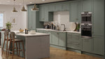 Modern kitchen with green cabinets, marble island, and stainless steel appliances.