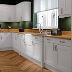 Modern kitchen with white cabinets, wooden countertops, and green walls.